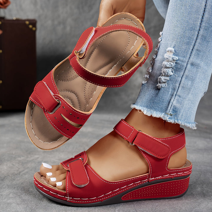 Red sandals worn with light blue jeans on a gray surface