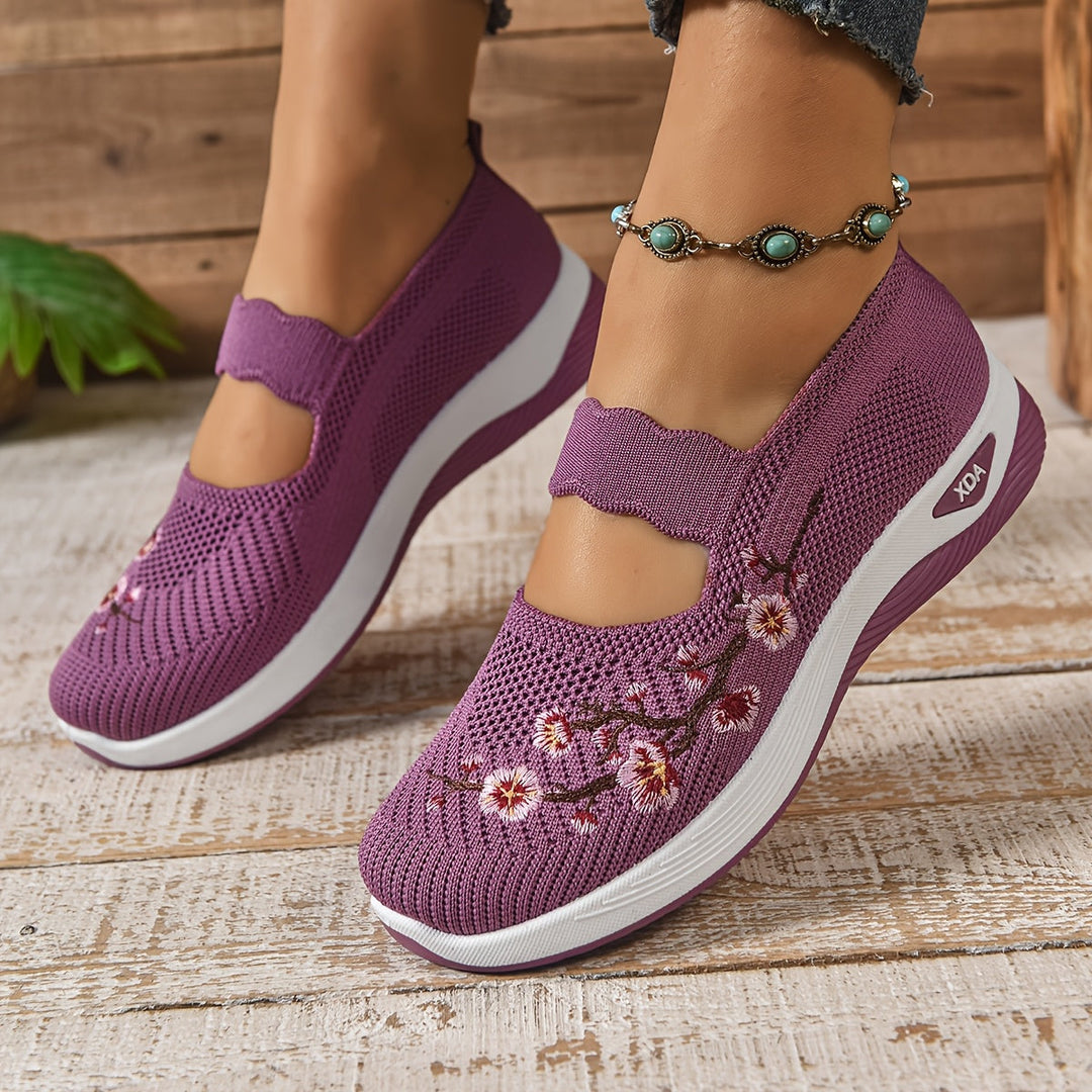 Purple slip-on shoes with floral design on a wooden floor