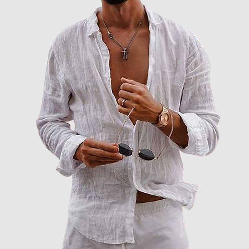 Man wearing a white linen shirt with sunglasses and a watch on a plain background