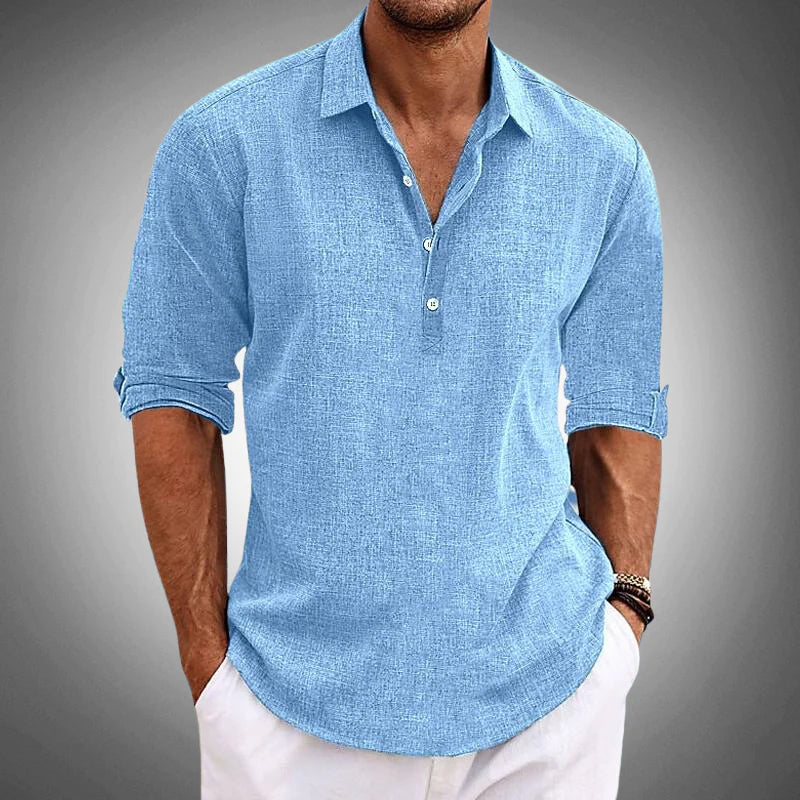 Man wearing a light blue button-up shirt with rolled-up sleeves on a gray background