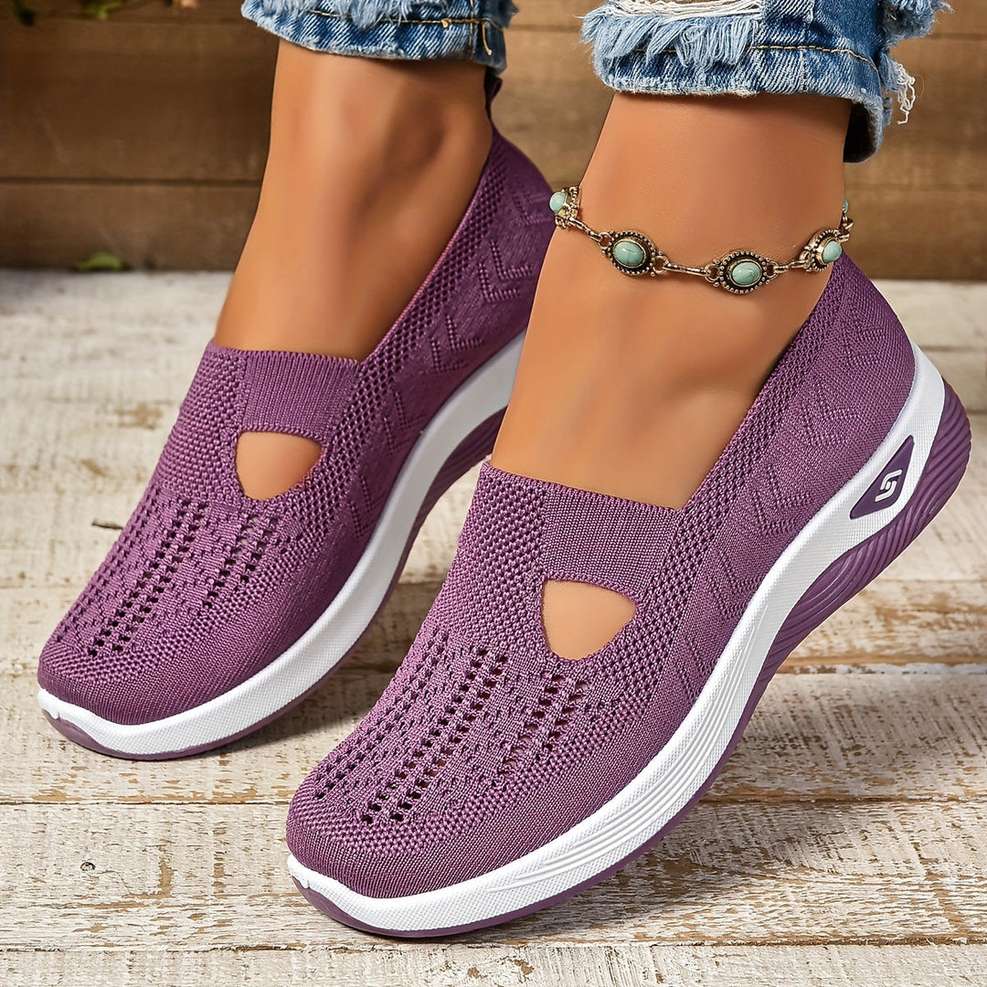 Purple slip-on shoes with white soles worn on a wooden surface