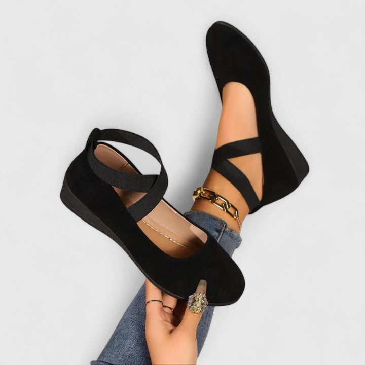 Black flat sandals worn with denim jeans on a light gray background